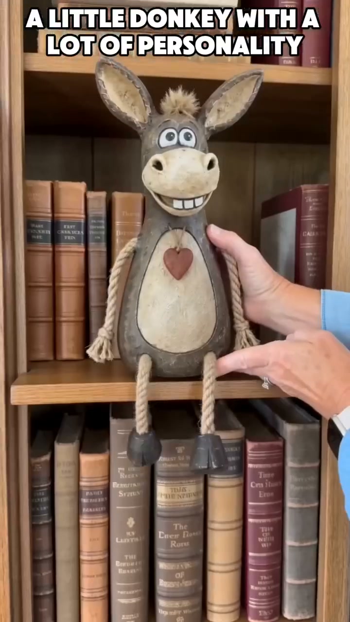 Rustic figurine of a donkey on a plank with rope legs hanging down