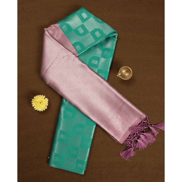 aqua green colour semi silk saree adorned with silver zari designs on the body, complemented by a contrasting pastel pink border and pallu